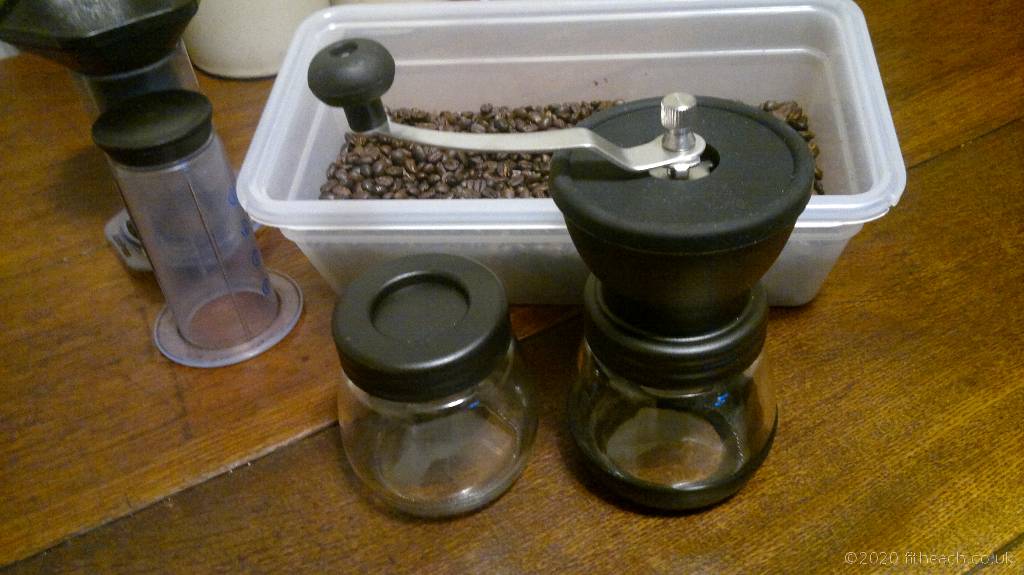 The Maison & White manual coffee grinder sitting beside my venerable AeroPress coffee brewer, and my container of roasted coffee beans.